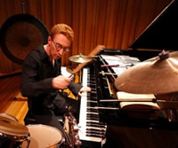 Danny Holt playing piano and percussion at the same time
